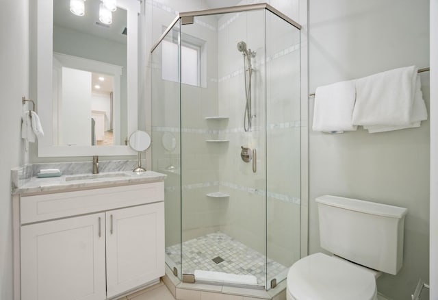 full bathroom featuring a stall shower, vanity, and toilet