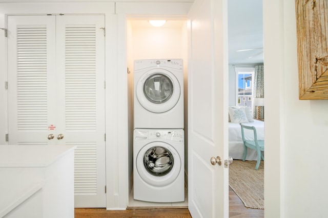 laundry room with stacked washing maching and dryer and wood finished floors