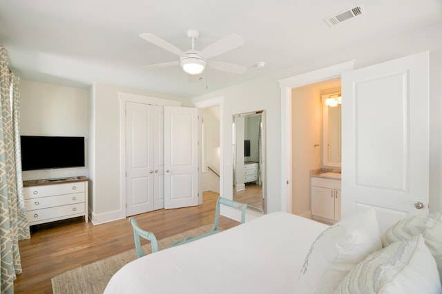 bedroom featuring light wood finished floors, a closet, visible vents, ensuite bathroom, and a ceiling fan