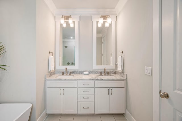 bathroom with a freestanding bath, double vanity, a sink, and baseboards