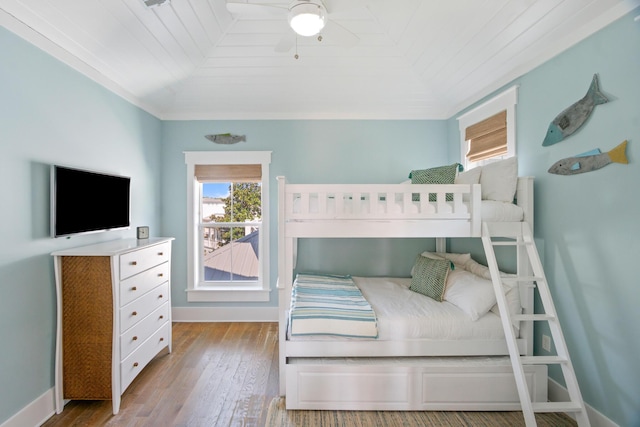 bedroom featuring a ceiling fan, baseboards, vaulted ceiling, and hardwood / wood-style floors