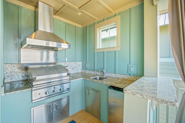 kitchen featuring light stone counters, refrigerator, a sink, wall chimney range hood, and green cabinetry