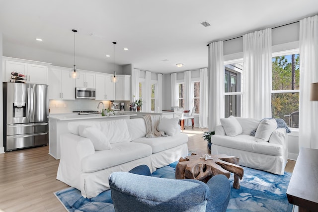 living room featuring light wood-style floors, visible vents, and recessed lighting