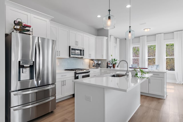 kitchen with stainless steel appliances, light countertops, decorative backsplash, a sink, and light wood-type flooring