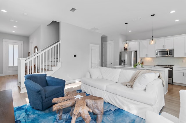 living room with light wood-style floors, stairs, baseboards, and recessed lighting