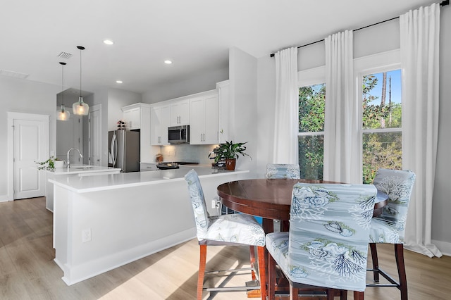 kitchen with tasteful backsplash, visible vents, white cabinets, stainless steel appliances, and light countertops