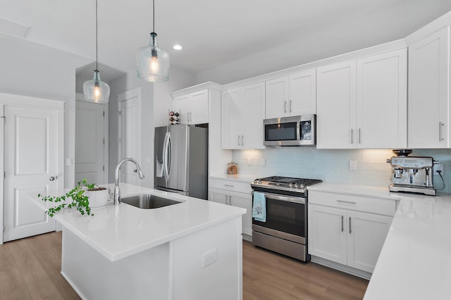 kitchen featuring decorative backsplash, appliances with stainless steel finishes, light wood-style floors, white cabinetry, and a sink