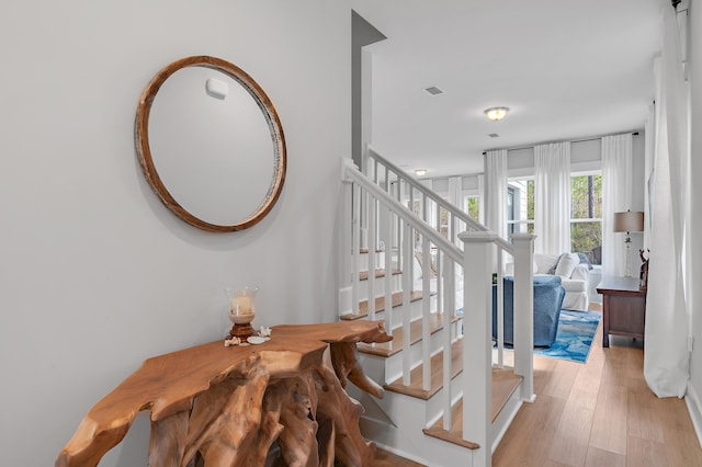 stairs with wood finished floors and visible vents