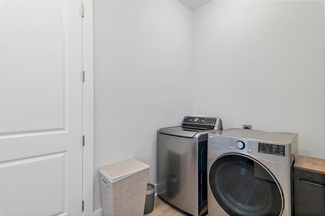 laundry room featuring laundry area, separate washer and dryer, and light wood-style flooring