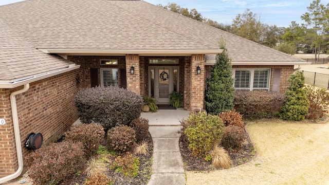 view of front of house with a shingled roof and brick siding