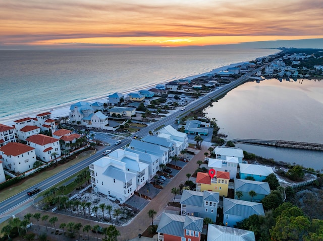 aerial view at dusk with a water view and a beach view