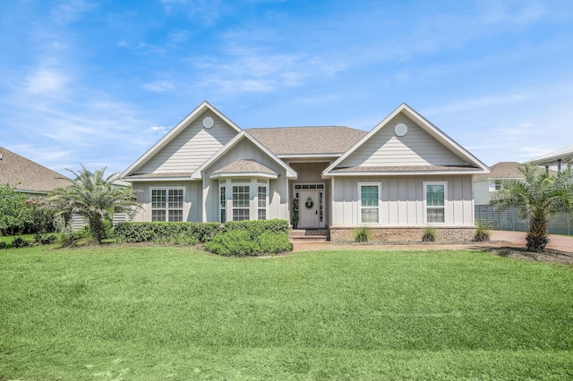 ranch-style house with brick siding, board and batten siding, a front yard, and a shingled roof