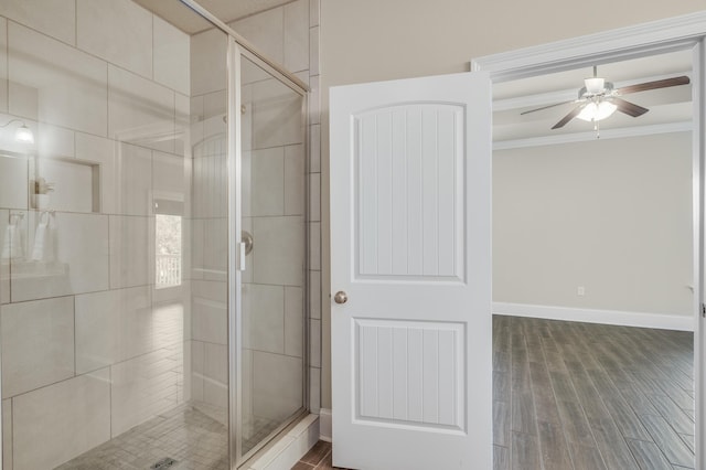 full bath with baseboards, ceiling fan, ornamental molding, wood finished floors, and a shower stall