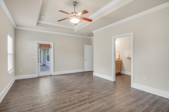 empty room with a tray ceiling, dark wood-style flooring, a ceiling fan, and baseboards