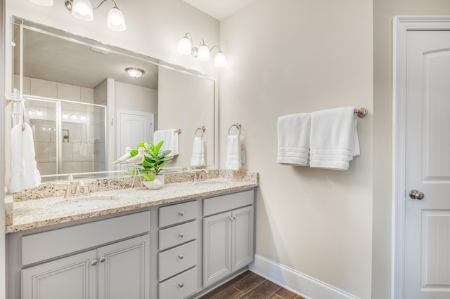 bathroom with double vanity, baseboards, a sink, and wood finish floors