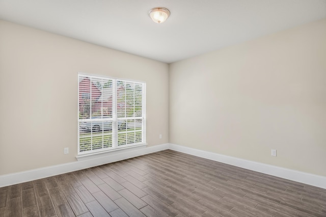 spare room featuring baseboards and wood finished floors