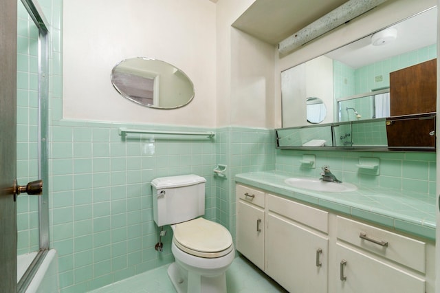 bathroom featuring vanity, toilet, a shower with shower door, and tile walls