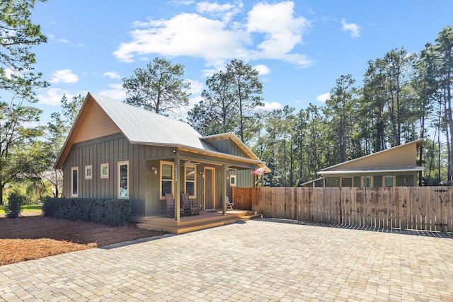 view of side of property featuring covered porch, a fenced front yard, and board and batten siding