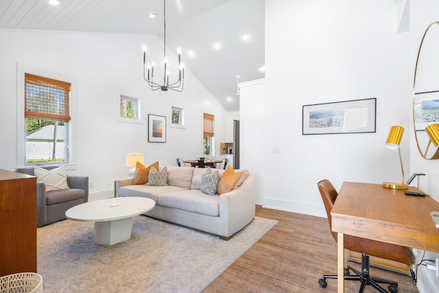 living area with high vaulted ceiling, recessed lighting, baseboards, light wood finished floors, and an inviting chandelier