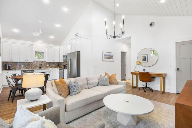 living area with recessed lighting, light wood-style flooring, baseboards, and an inviting chandelier