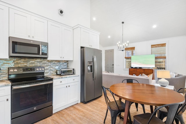 kitchen with white cabinets, light stone counters, and stainless steel appliances