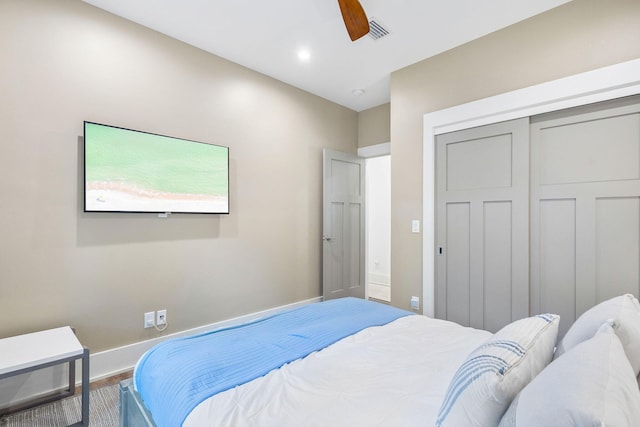 bedroom with baseboards, visible vents, a ceiling fan, wood finished floors, and a closet