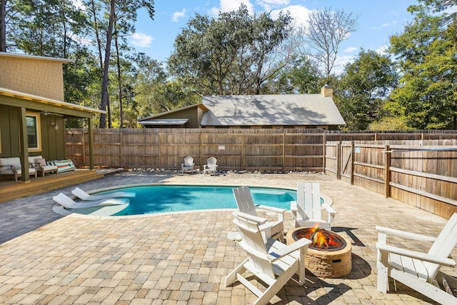 view of swimming pool featuring a deck, an outdoor fire pit, a fenced backyard, and a fenced in pool