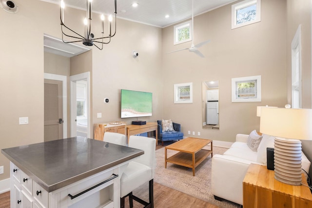 living area with light wood-style flooring, a high ceiling, baseboards, and recessed lighting