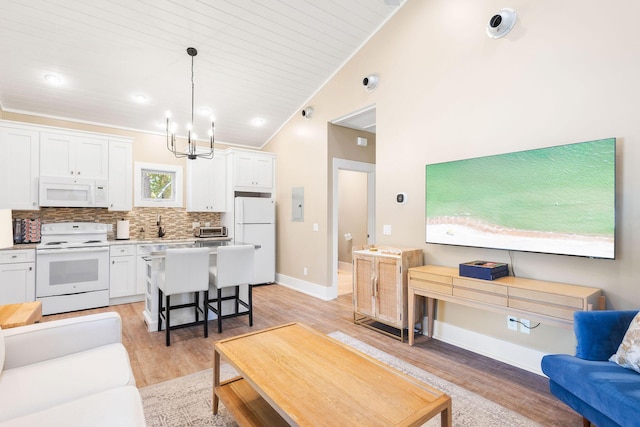 living room with a toaster, baseboards, lofted ceiling, light wood-type flooring, and a chandelier