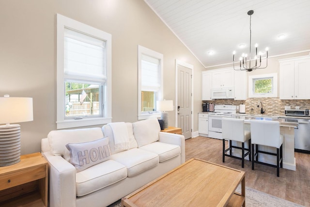 living area featuring lofted ceiling, an inviting chandelier, wood finished floors, and a toaster