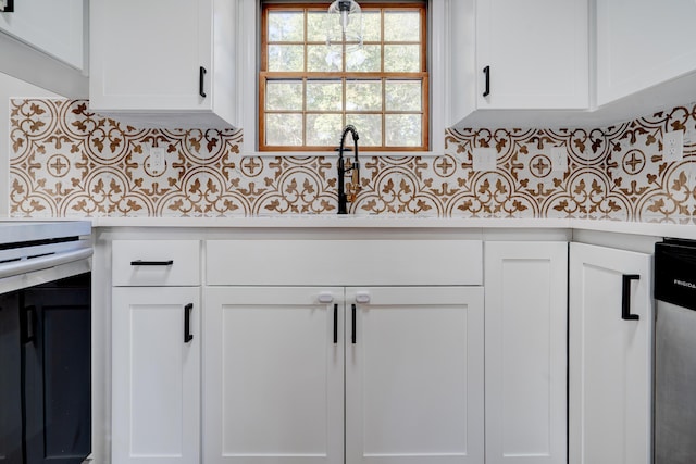 kitchen featuring light countertops, stainless steel dishwasher, backsplash, and white cabinets