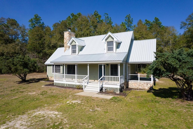 view of front facade with a porch, metal roof, a chimney, and a front lawn