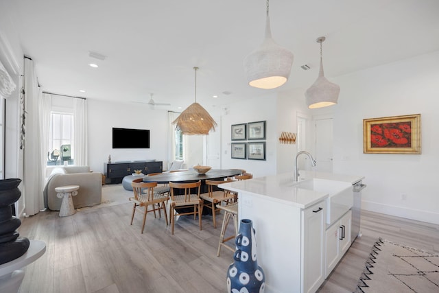 kitchen featuring light wood finished floors, visible vents, open floor plan, white cabinets, and a sink