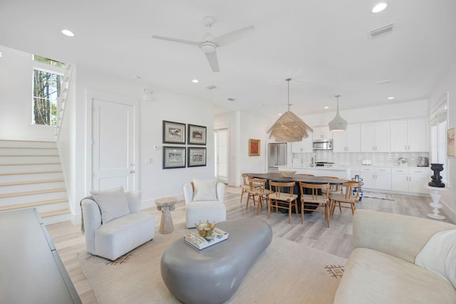 living area with light wood-style flooring, recessed lighting, visible vents, and stairway