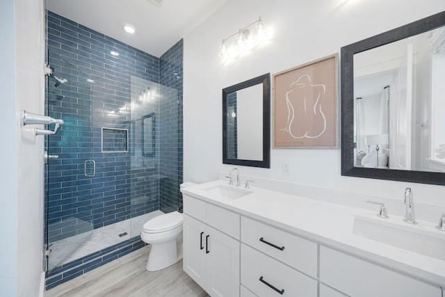 full bath featuring toilet, a stall shower, double vanity, and a sink