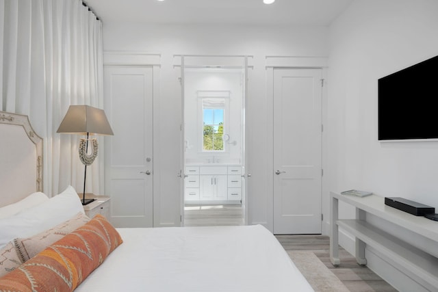 bedroom with recessed lighting, a sink, and light wood finished floors