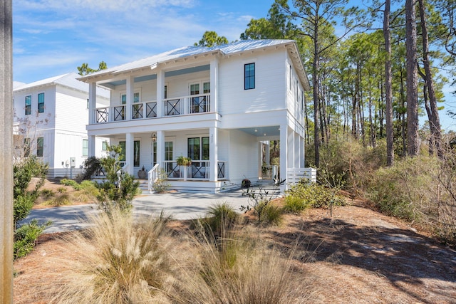 view of front facade with metal roof, a porch, a standing seam roof, and a balcony