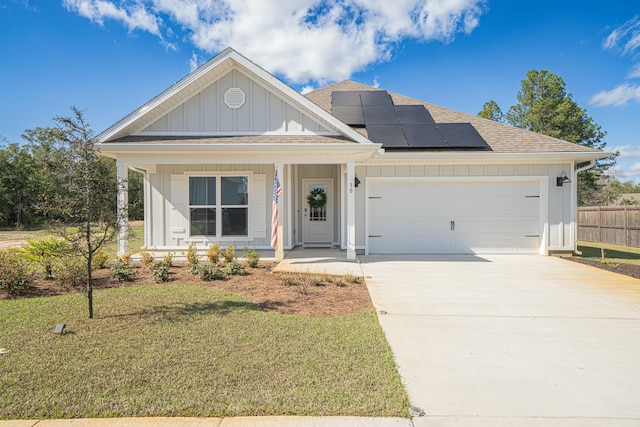 view of front of property with covered porch, a front yard, a garage, and solar panels