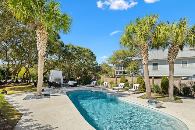 view of swimming pool with a fenced in pool, fence, a lit fireplace, and a patio area