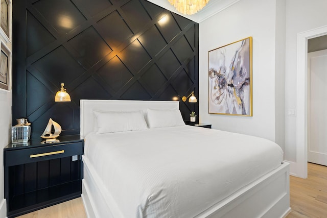 bedroom featuring light wood finished floors, a decorative wall, and an accent wall