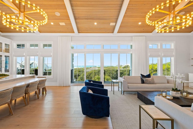 living room with beamed ceiling, a notable chandelier, light wood-style flooring, and a towering ceiling