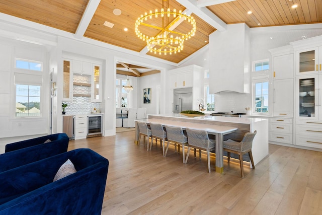 dining area featuring wine cooler, beamed ceiling, wooden ceiling, an inviting chandelier, and light wood-style floors