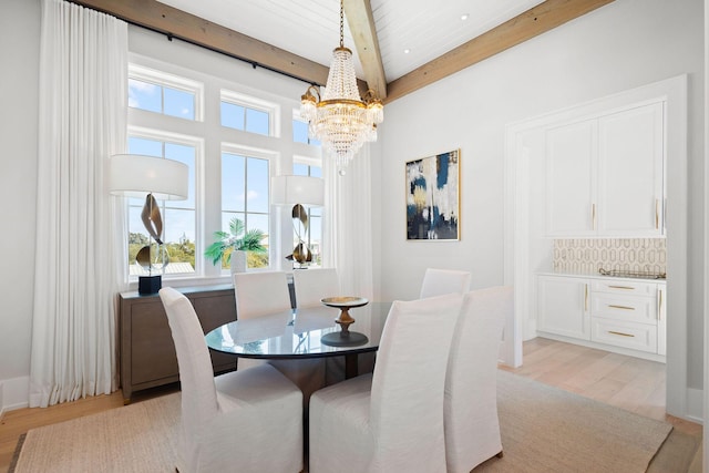 dining room featuring beam ceiling, light wood finished floors, and an inviting chandelier