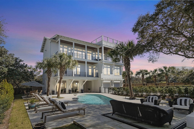 back of house featuring an outdoor living space, fence, an outdoor pool, a balcony, and a patio area