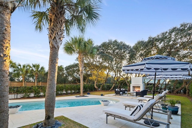 view of swimming pool with a patio, fence, a fenced in pool, and a lit fireplace