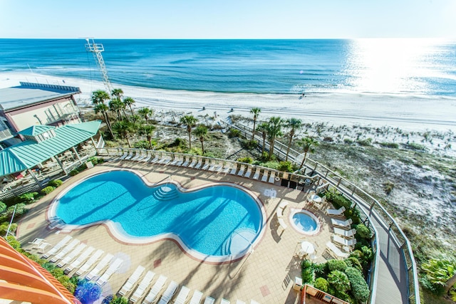 view of swimming pool with a water view and a beach view