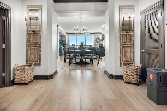 hall with baseboards, ornamental molding, wood finished floors, and an inviting chandelier