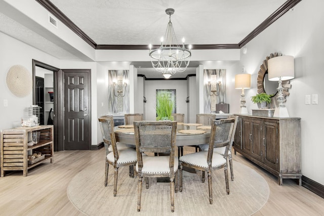 dining area featuring visible vents, light wood-style flooring, an inviting chandelier, ornamental molding, and baseboards