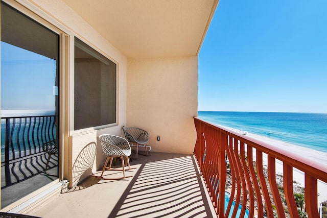 balcony with a water view, a view of the beach, and a sunroom