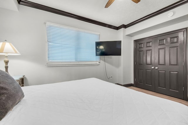 bedroom with a closet, ornamental molding, a ceiling fan, a textured ceiling, and wood finished floors